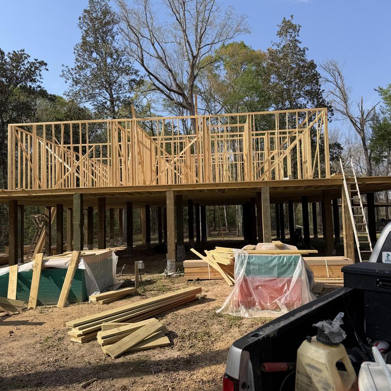 Wooden wall framing on elevated foundation with lumber nearby