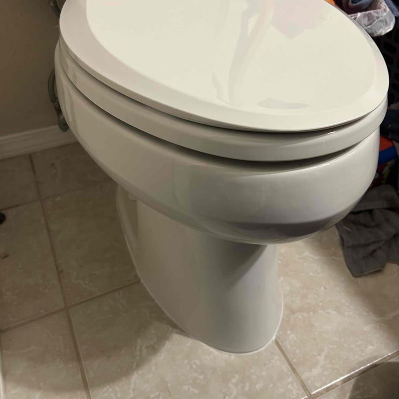 Toilet bowl with closed lid in tiled bathroom