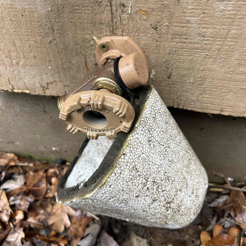 Outside faucet with foam insulation on siding wall
