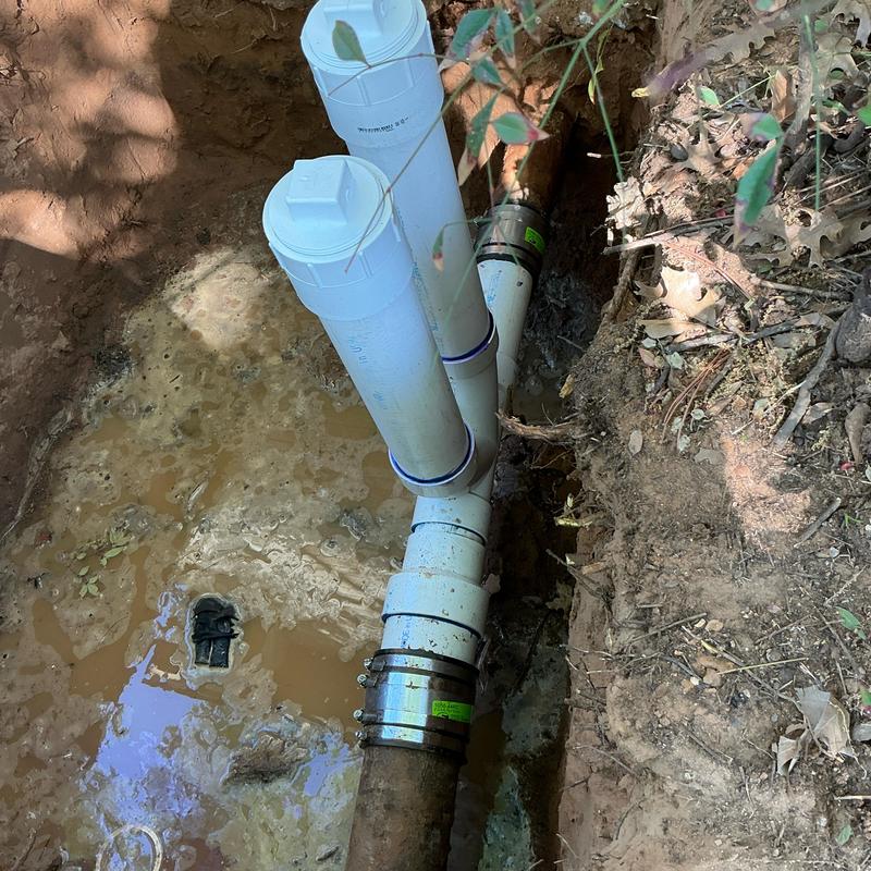 PVC two-way clean outs installation in muddy trench