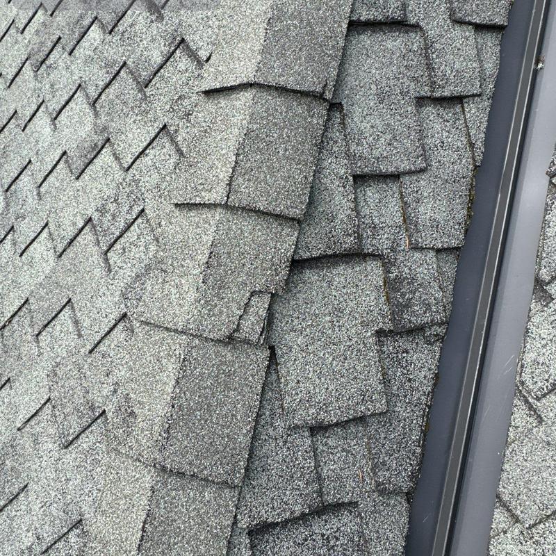 Asphalt shingles showing multiple cracks near metal flashing
