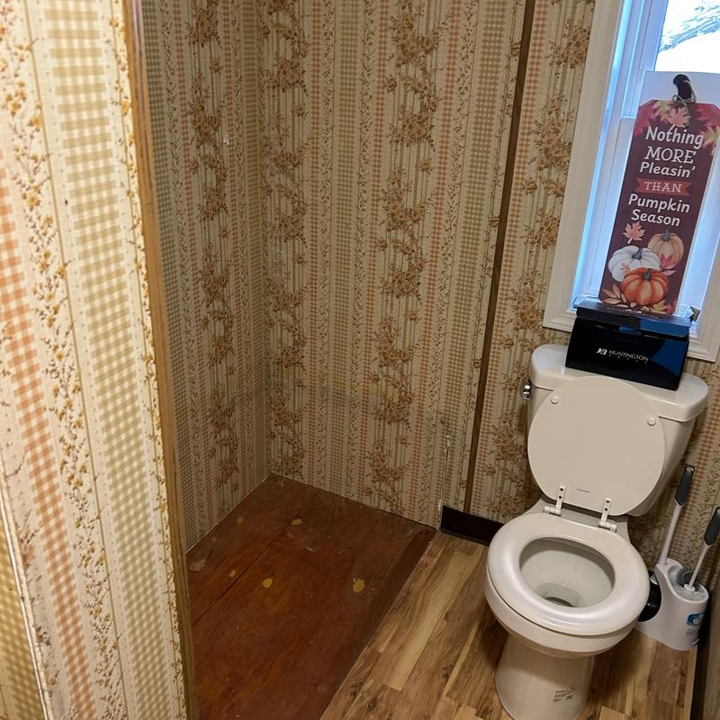 Bathtub removal area with toilet and floral wallpaper Bathtub removal area with toilet and floral wallpaper