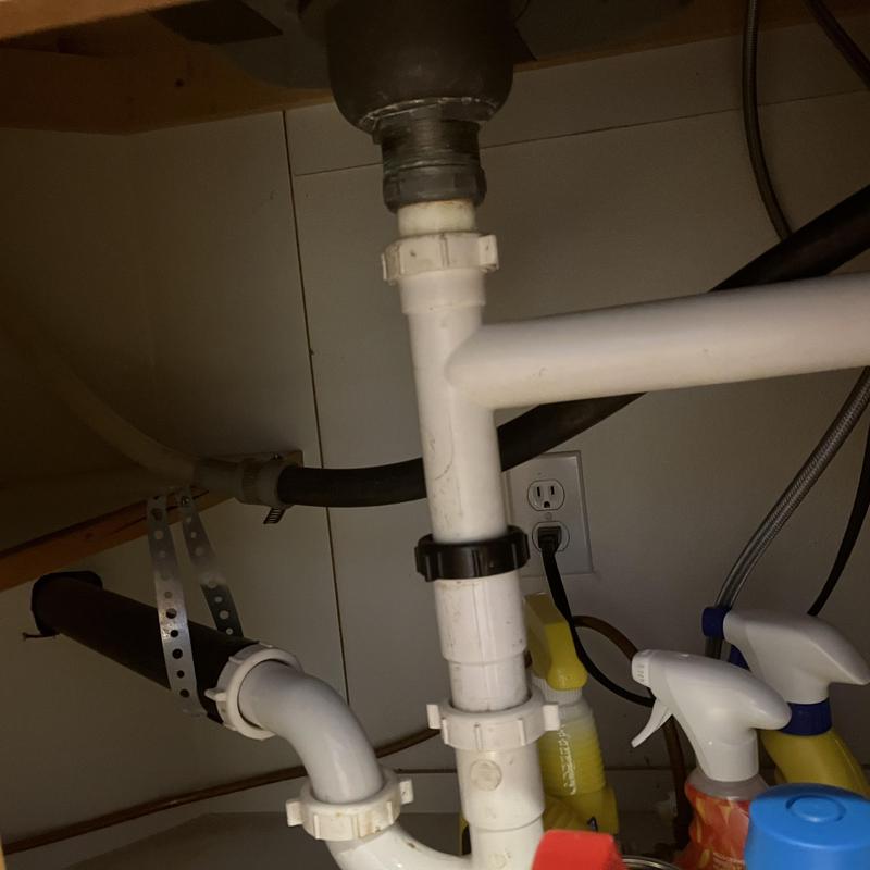 Kitchen sink PVC drain pipes under cabinet with spray bottles