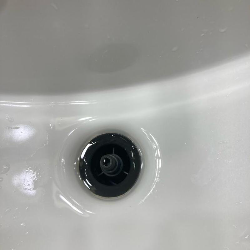 Bathroom sink drain with water droplets in basin Bathroom sink drain with water droplets in basin