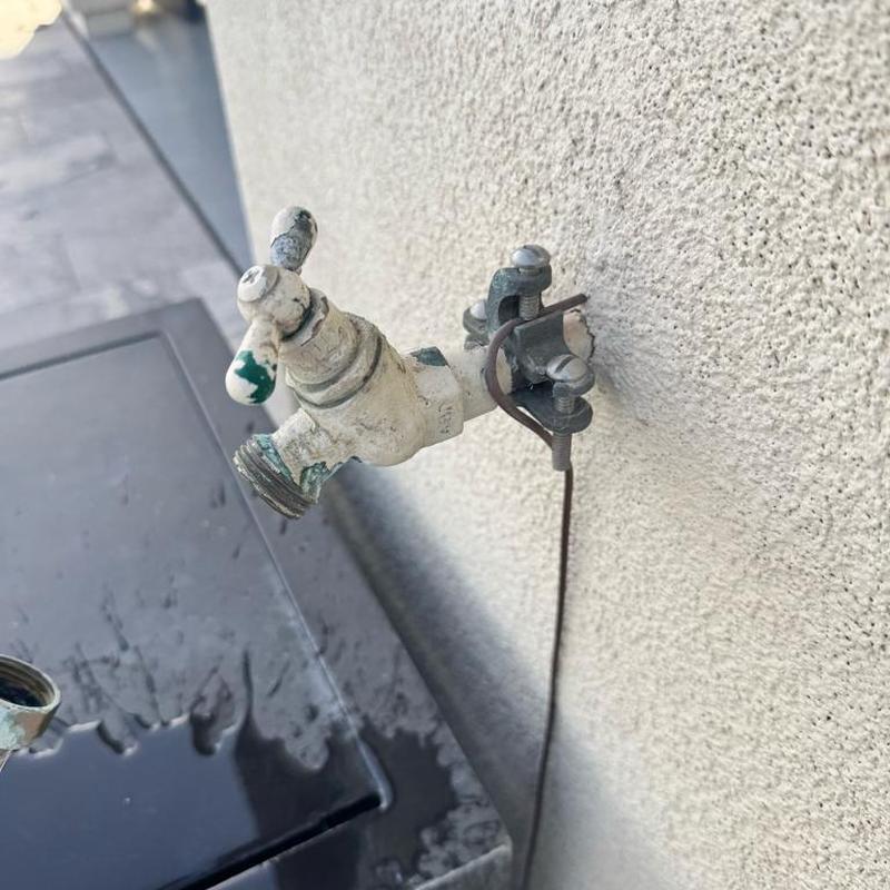 Hose bib valve leaking on exterior wall with water pooling