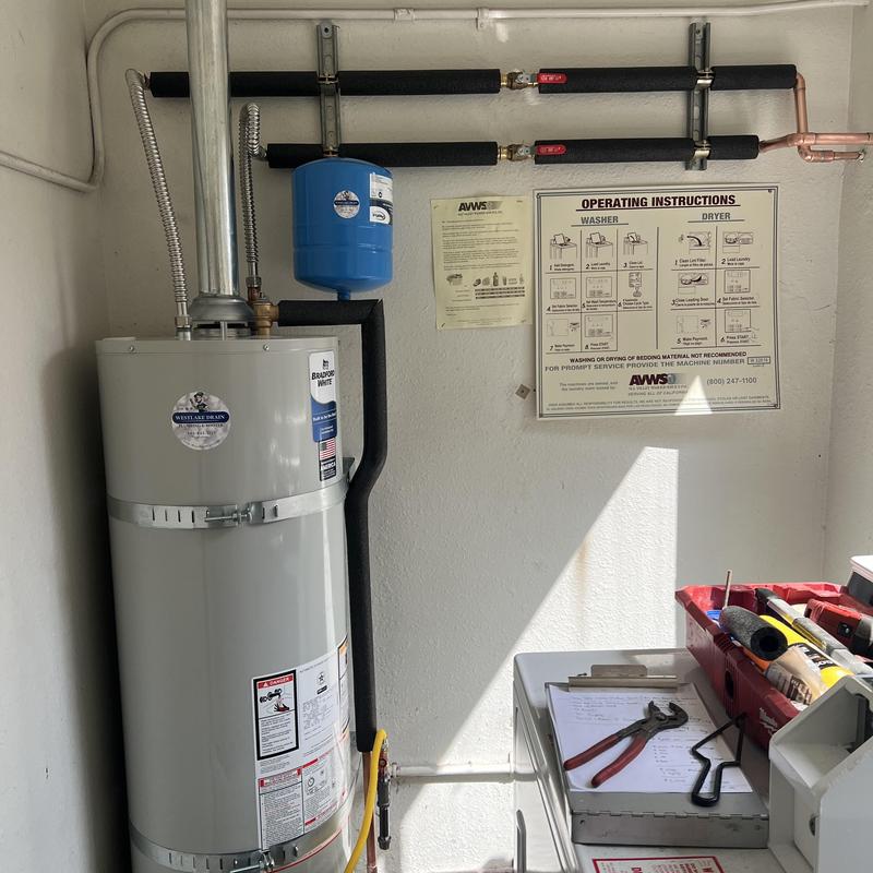 Water heater with pipes and expansion tank in laundry room