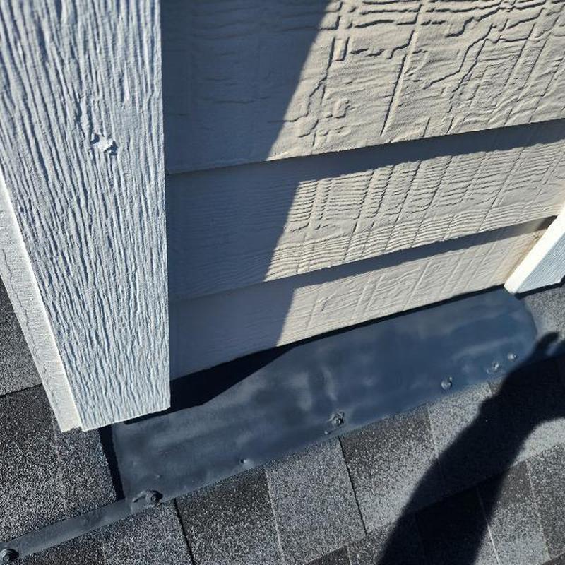 Chimney cricket flashing with sealed fasteners on roof