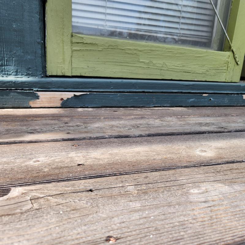 Wood door threshold and siding with paint damage