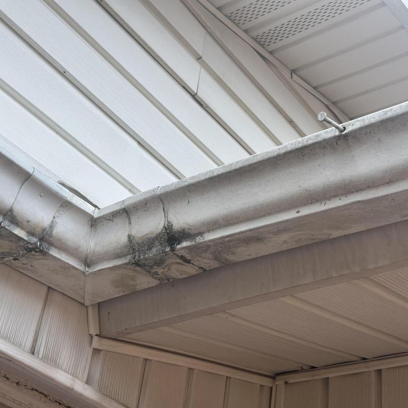 Gutter corner with dirt and staining near soffit siding
