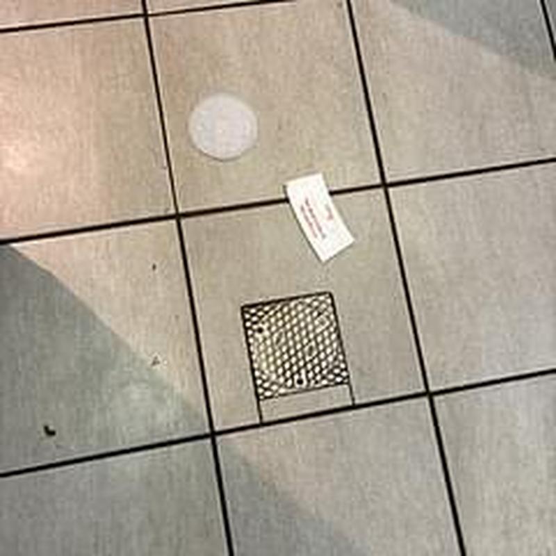 Floor drain with metal grate and clean out cover on tile