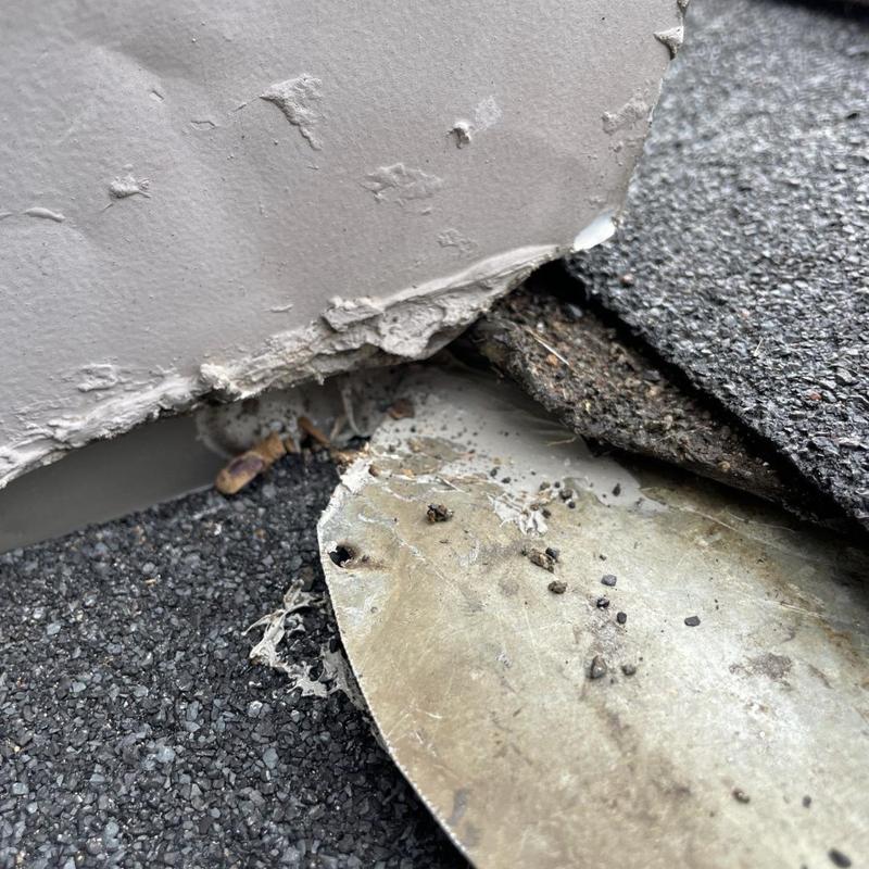 Roof flashing at siding wall-roof junction with damage
