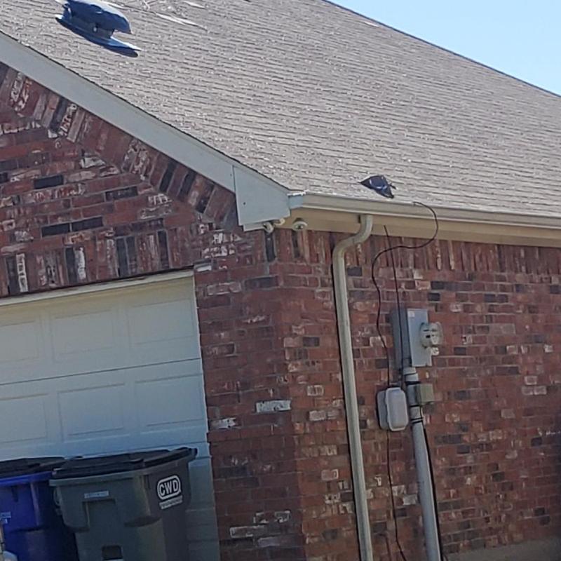 Asphalt roof shingles with hail damage on brick house