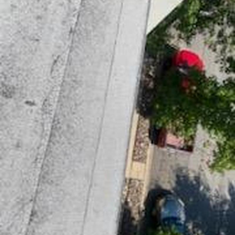 Flat roof surface inspection with worker in red shirt