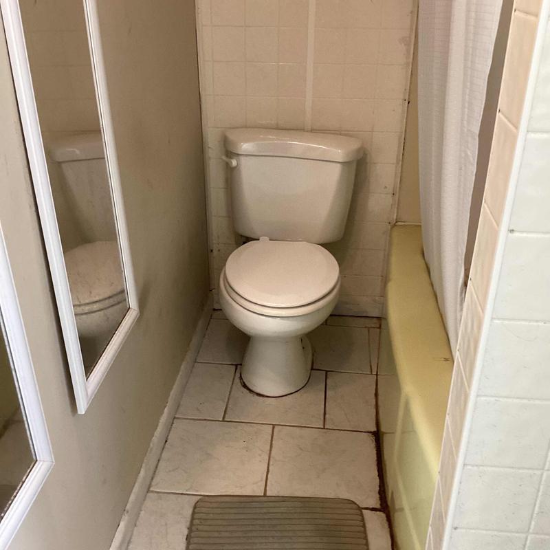 Toilet installation in small bathroom with tiled floor