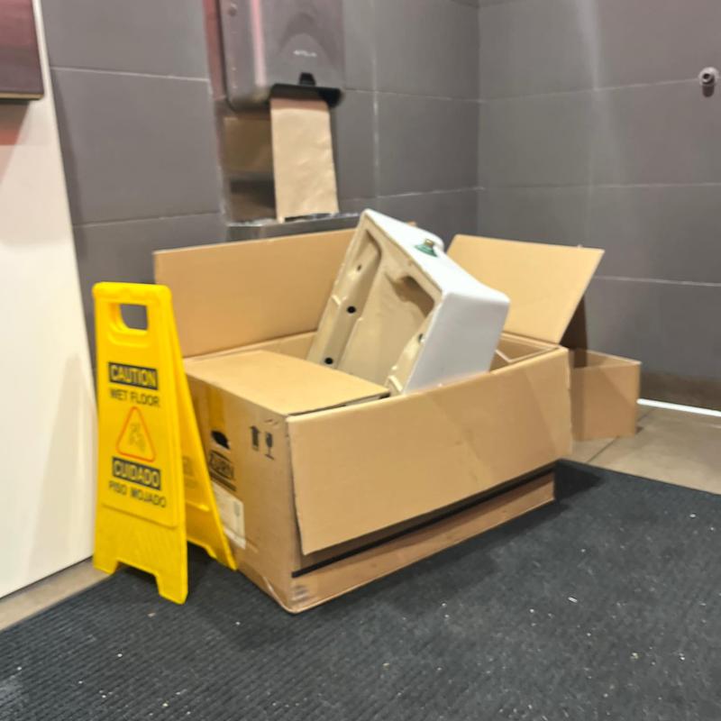 Urinal fixture in packaging next to caution sign