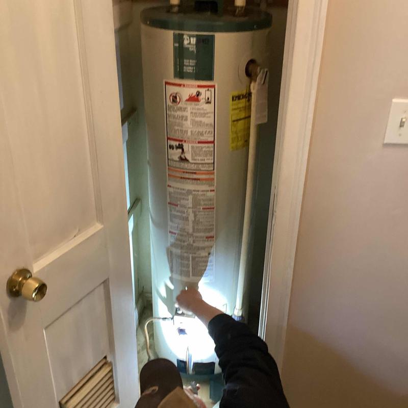 Water heater pilot light being relit in closet