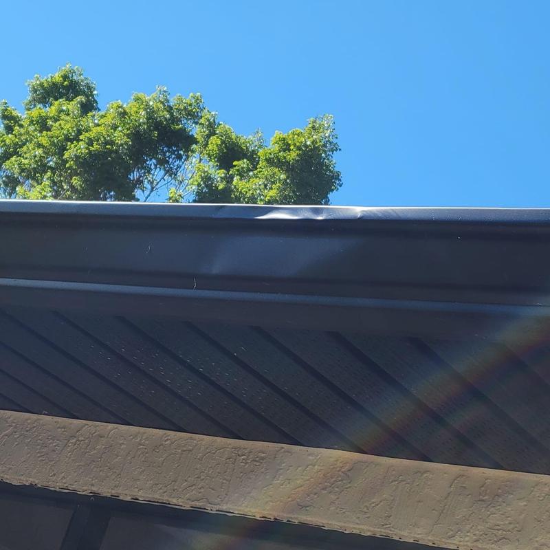 Metal gutter with minor dent and clear blue sky