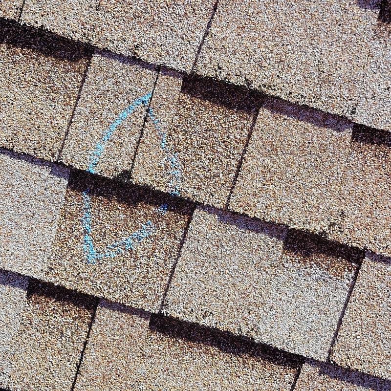 Shingle roof with chalk-marked damaged area