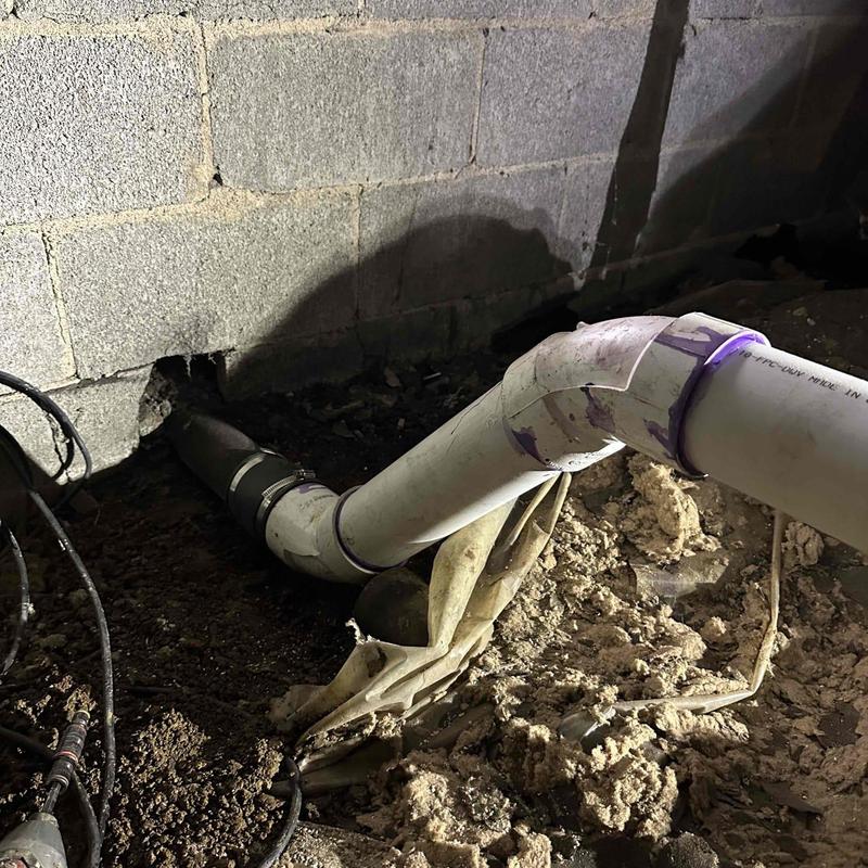 PVC drain pipe installation in crawl space with dirt floor