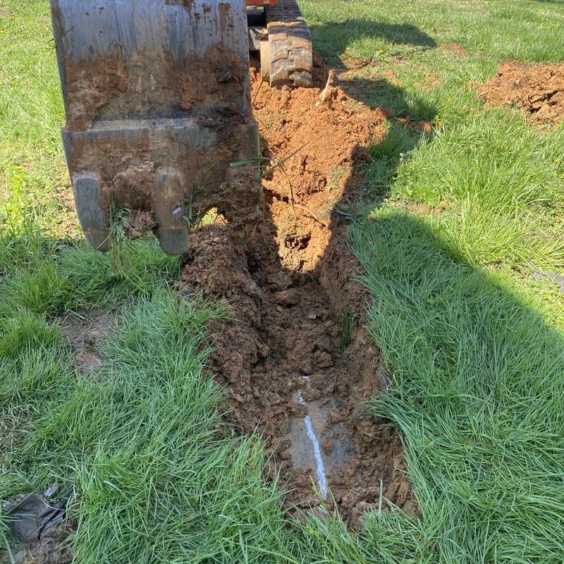 Jetted sewer line with excavator digging trench