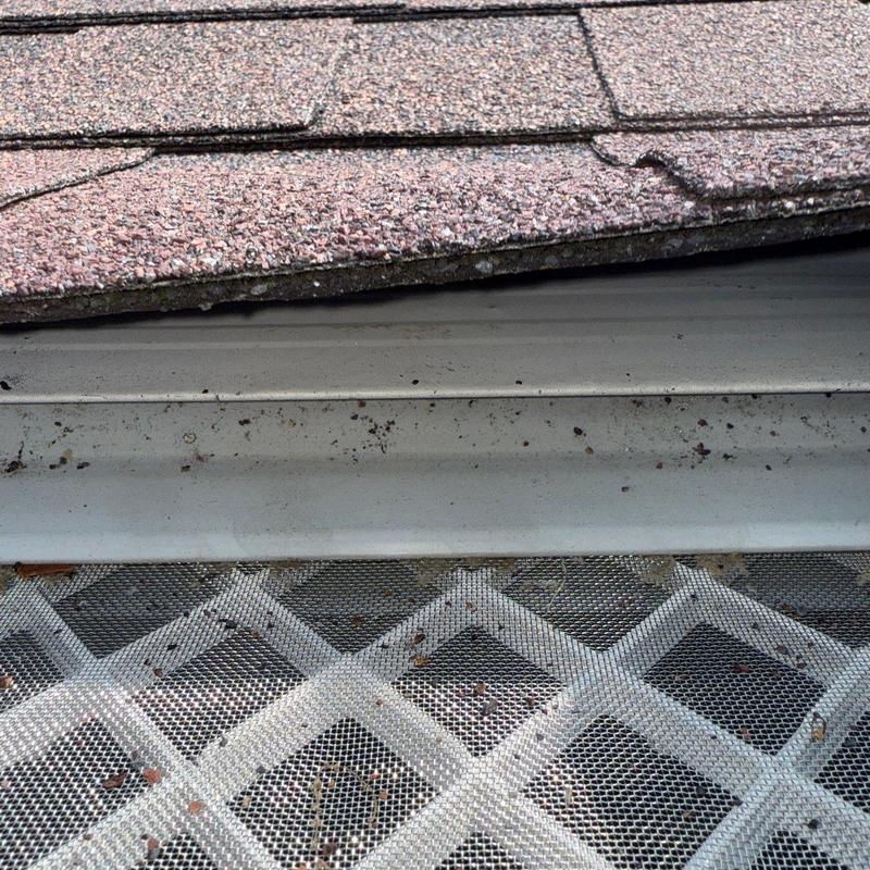 Asphalt shingles with hail and wind damage on roof edge