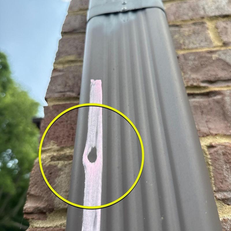 Metal flashing with hail damage marked by paint circle