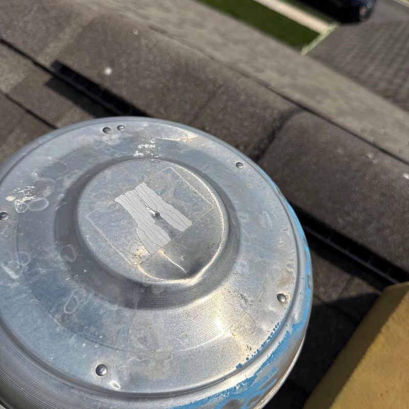Roof vent inspection on shingle roofing, hail damage visible