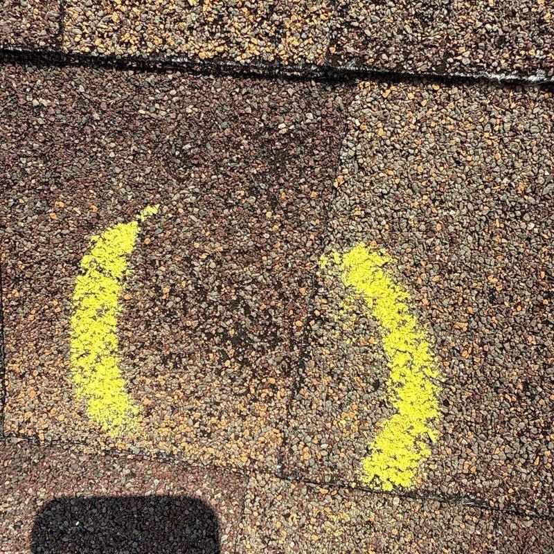 Roof shingle hail damage marked with yellow spray paint
