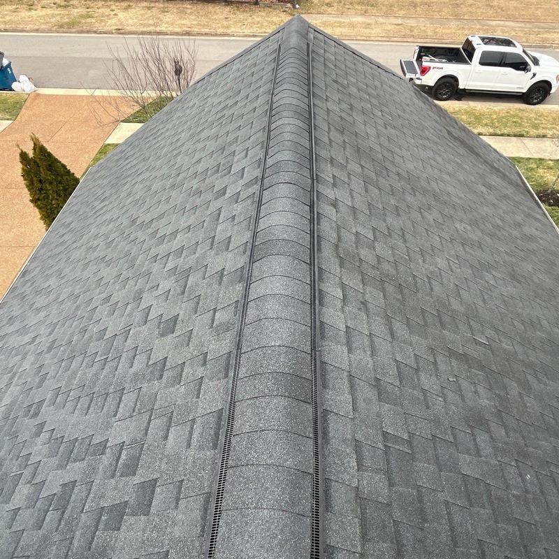 Asphalt shingle roof with ridge vent and driveway view