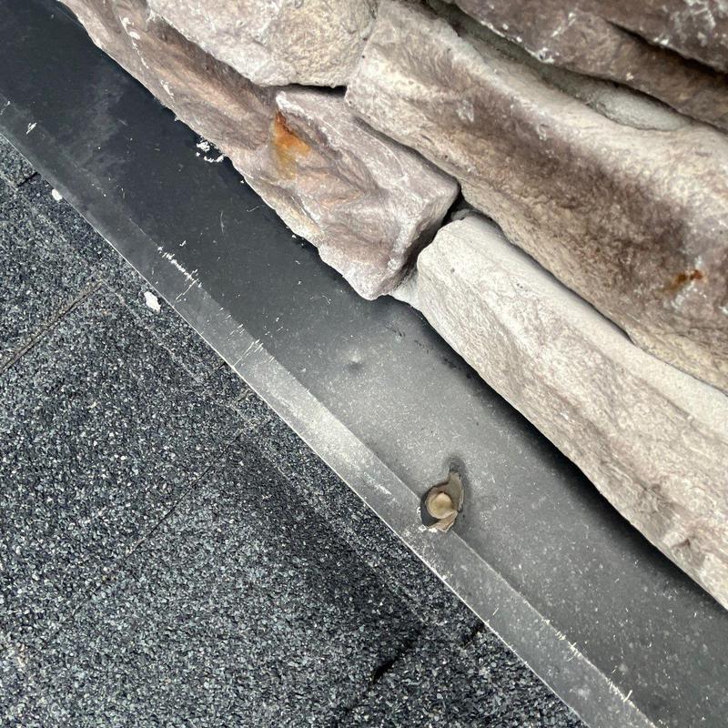 Roof flashing with hail damage near stone veneer