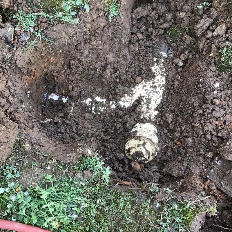 Septic tank inlet pipe exposed in soil excavation