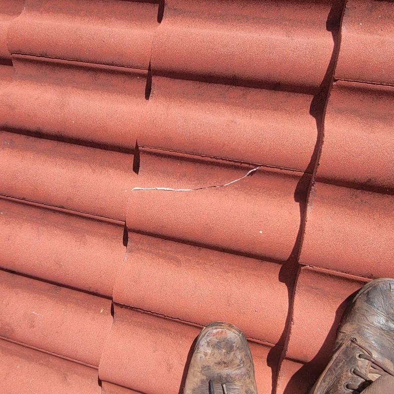 Concrete tile roof with cracked tiles and old repairs