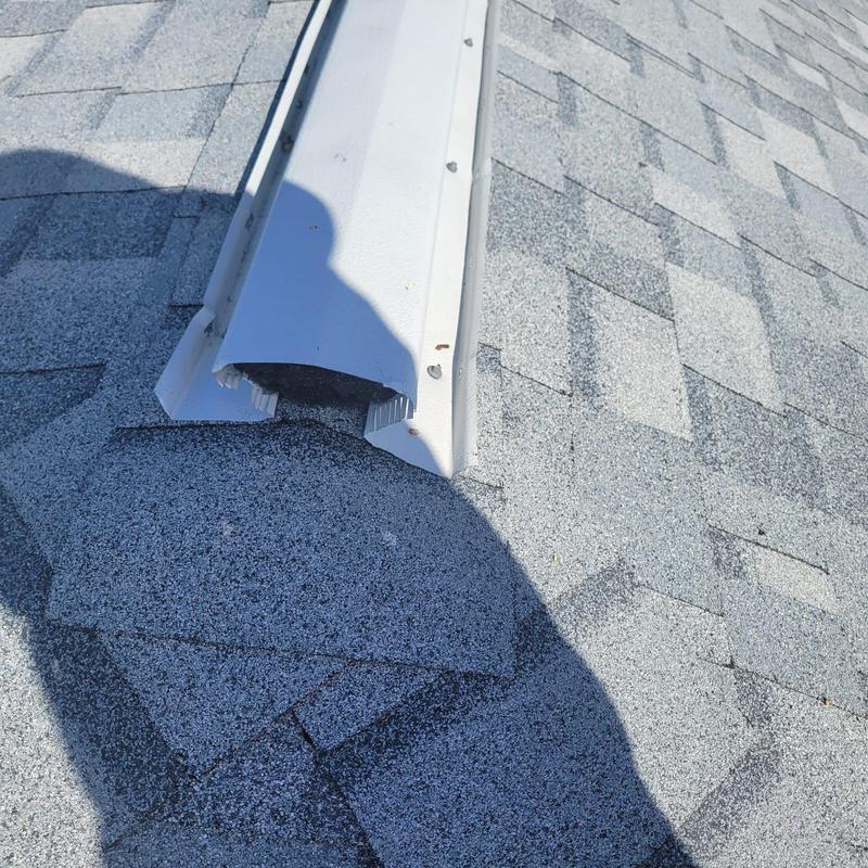Hip cap shingles on shingle roof with metal ridge vent