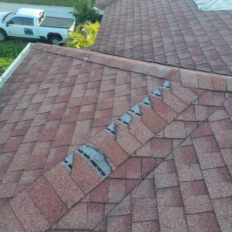 Shingle roof ridge with missing and damaged cap shingles