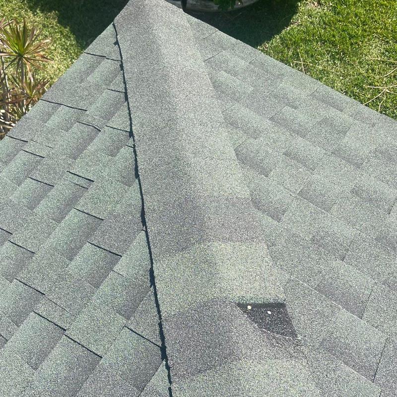 Shingle roof ridge with repaired cap shingles