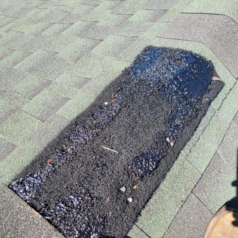Shingle roof patch with black sealant on aged shingles