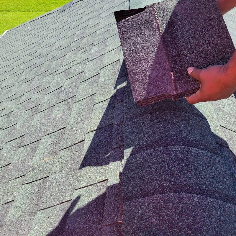 Cap shingles on older roof with hand holding shingles