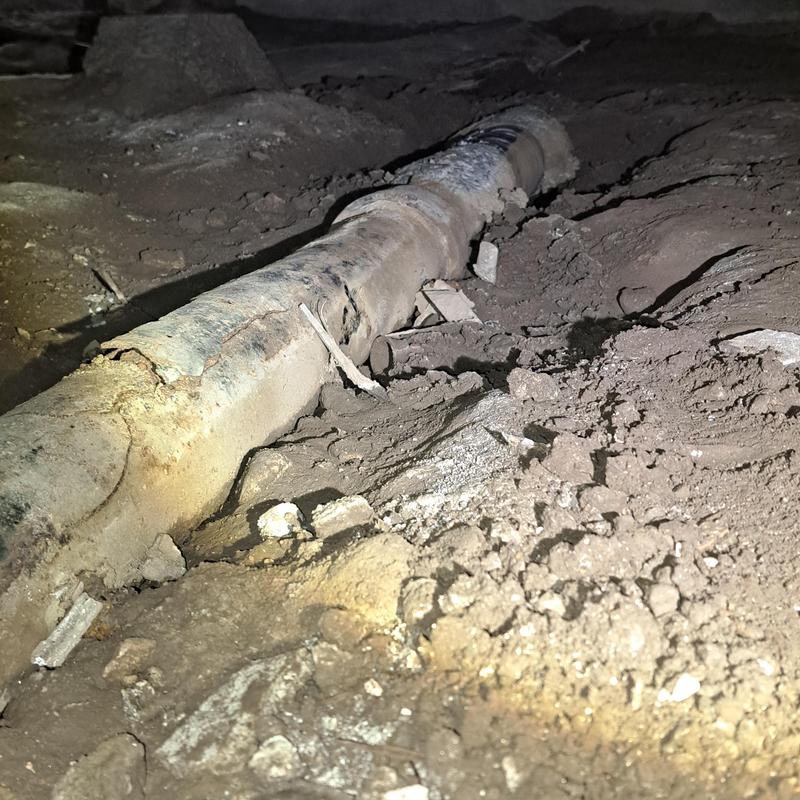 Cast iron drain pipe under house in dirt crawlspace