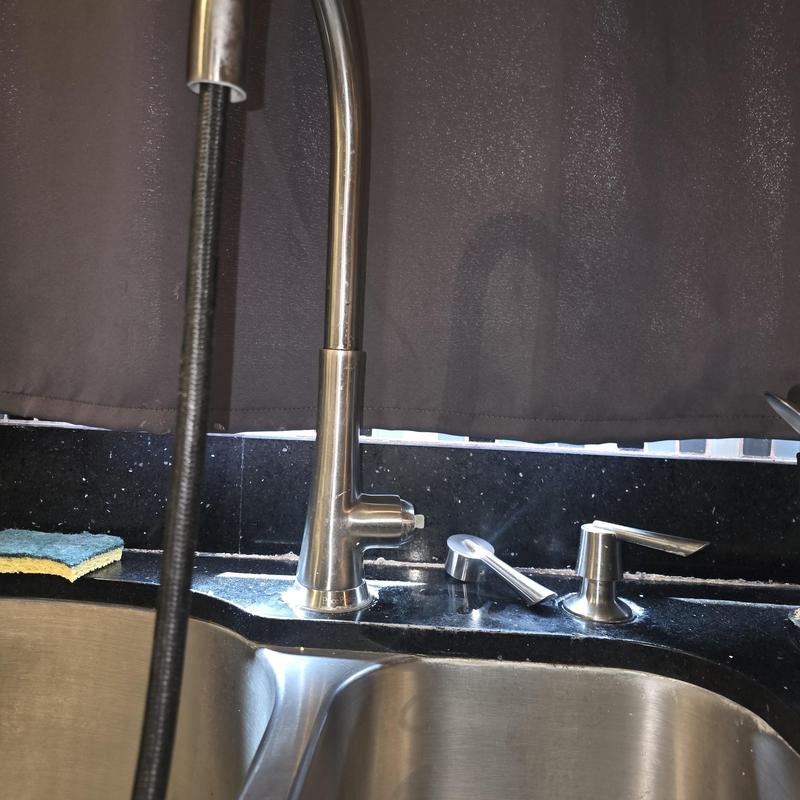 Kitchen faucet with soap dispenser on black countertop Kitchen faucet with soap dispenser on black countertop