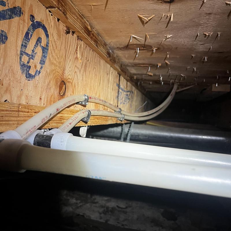 Pex piping in crawl space with clamps and fittings