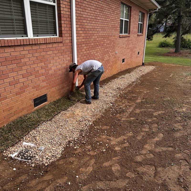 French drain pipe installation with gravel netting near house