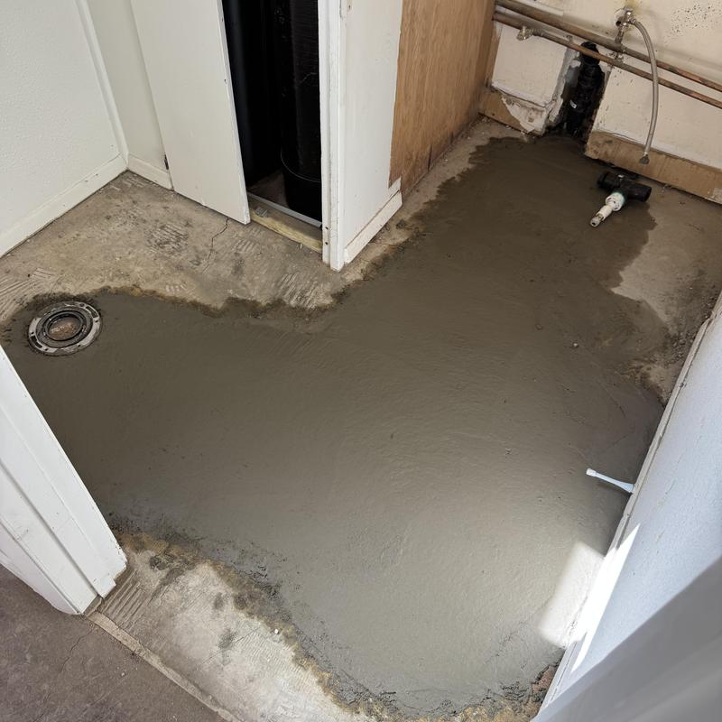 Concrete floor patch around plumbing drain and pipes