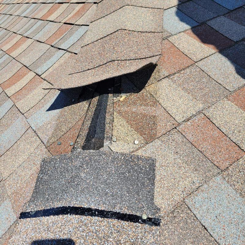 Shingle roof with lifted damaged shingles visible