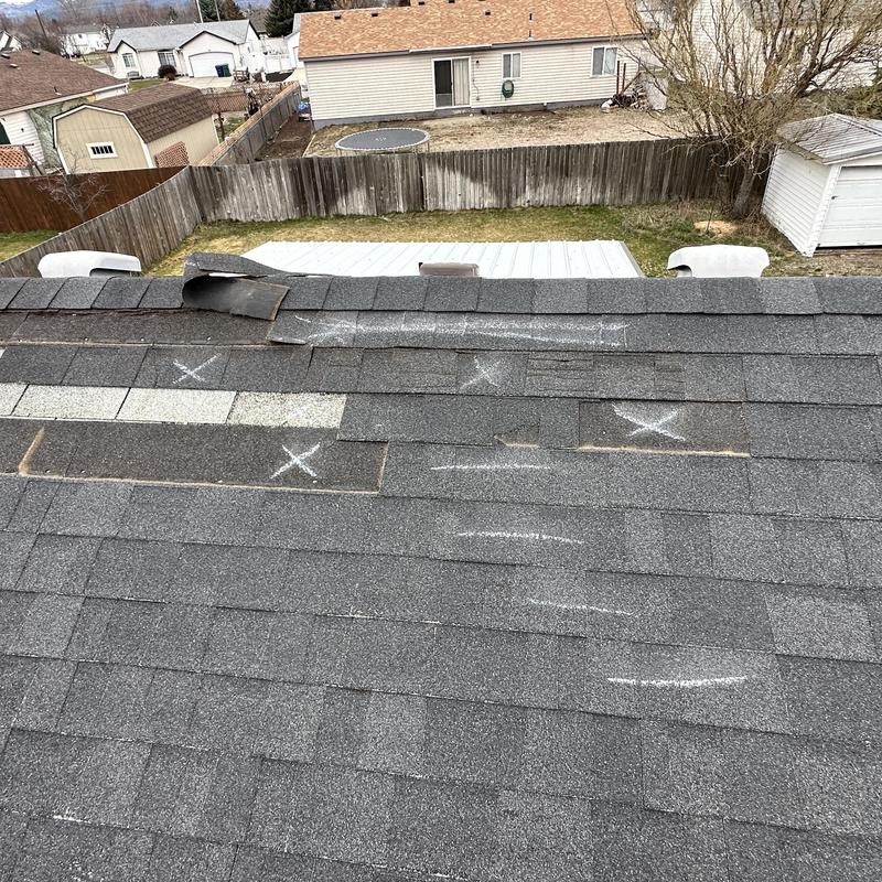 Asphalt shingle roof with wind damage and chalk markings