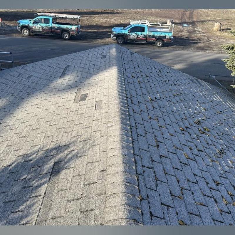 Asphalt shingle roof ridge during inspection with company trucks