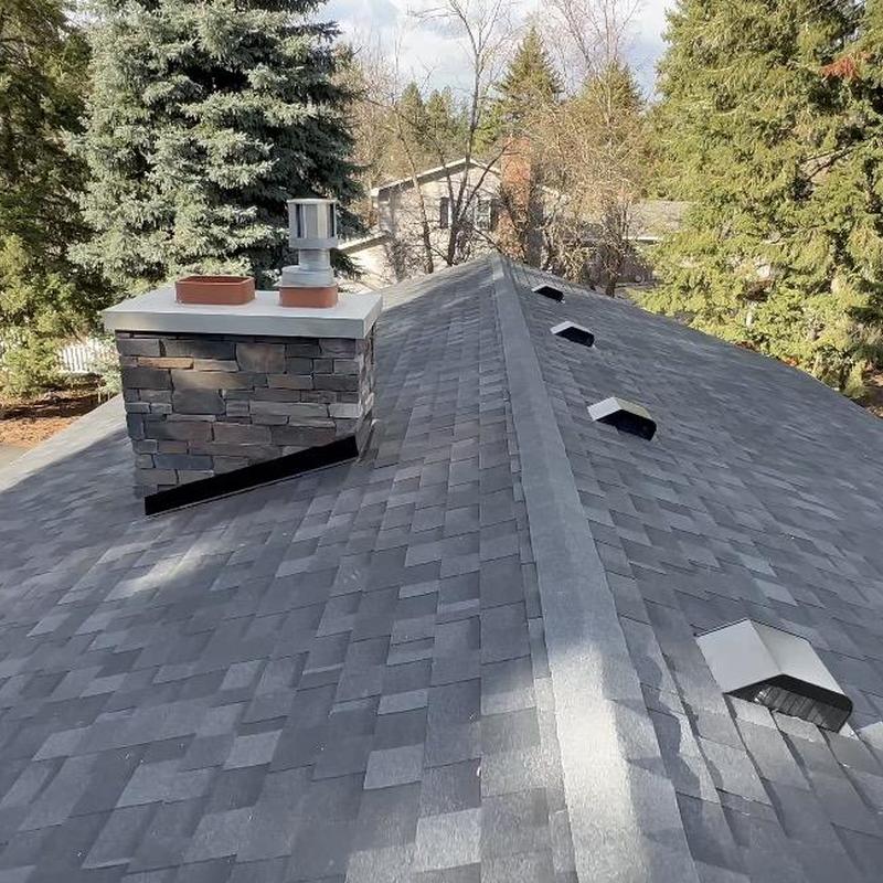Asphalt shingle roof with new ridge vents and chimney cap
