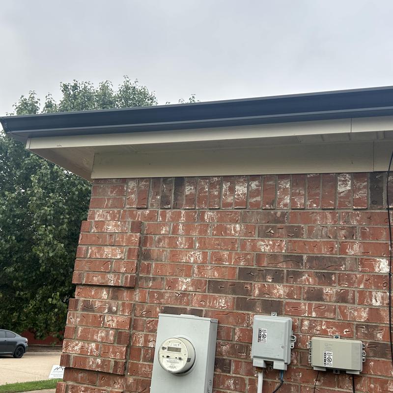 Black gutter and downspout on brick wall