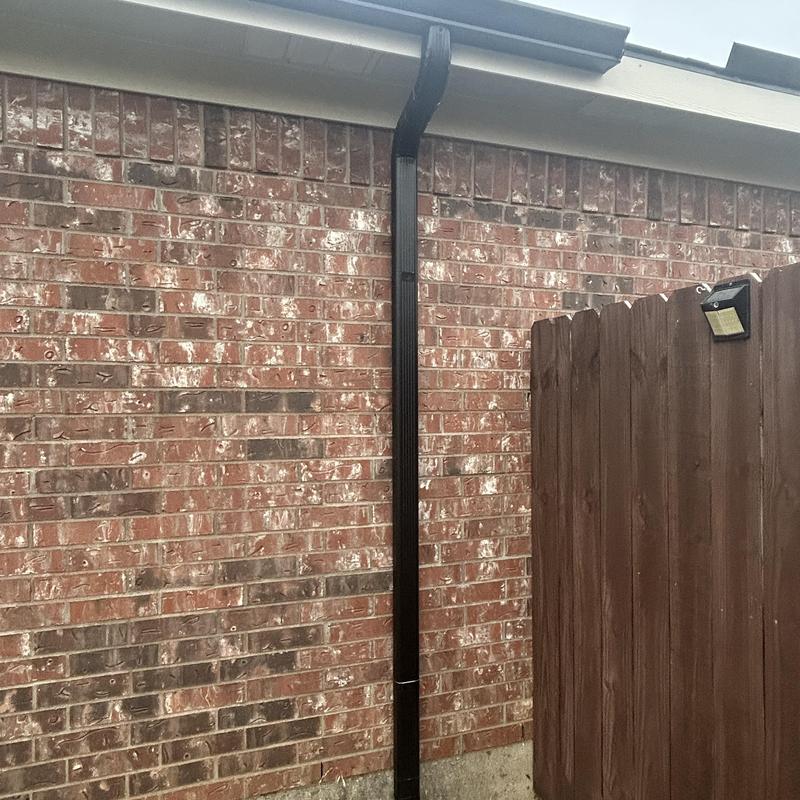 Black gutter downspout on brick wall in Crowley TX