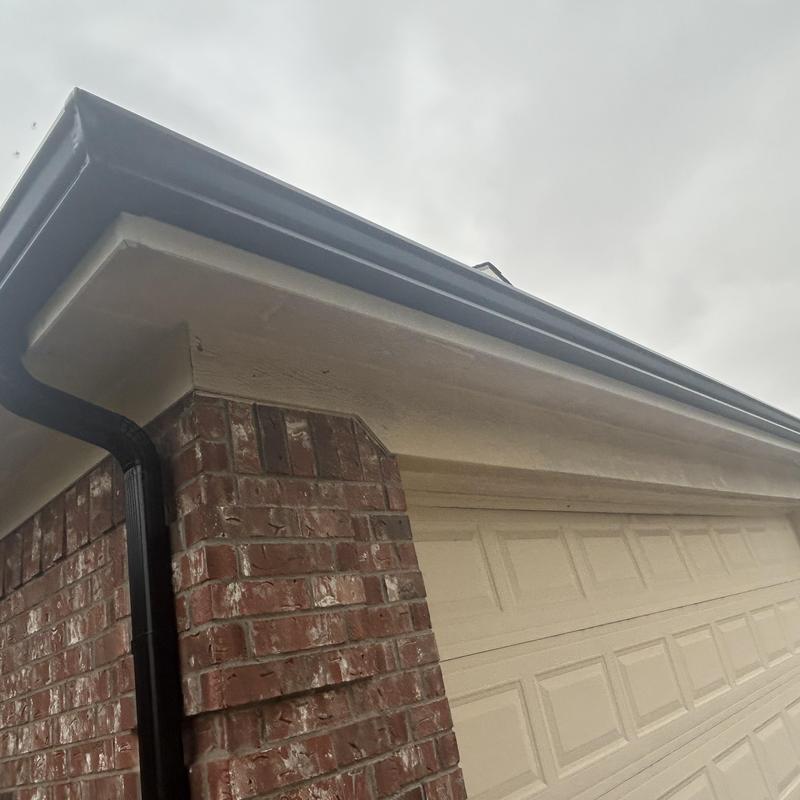 Black gutter and downspout on brick home exterior