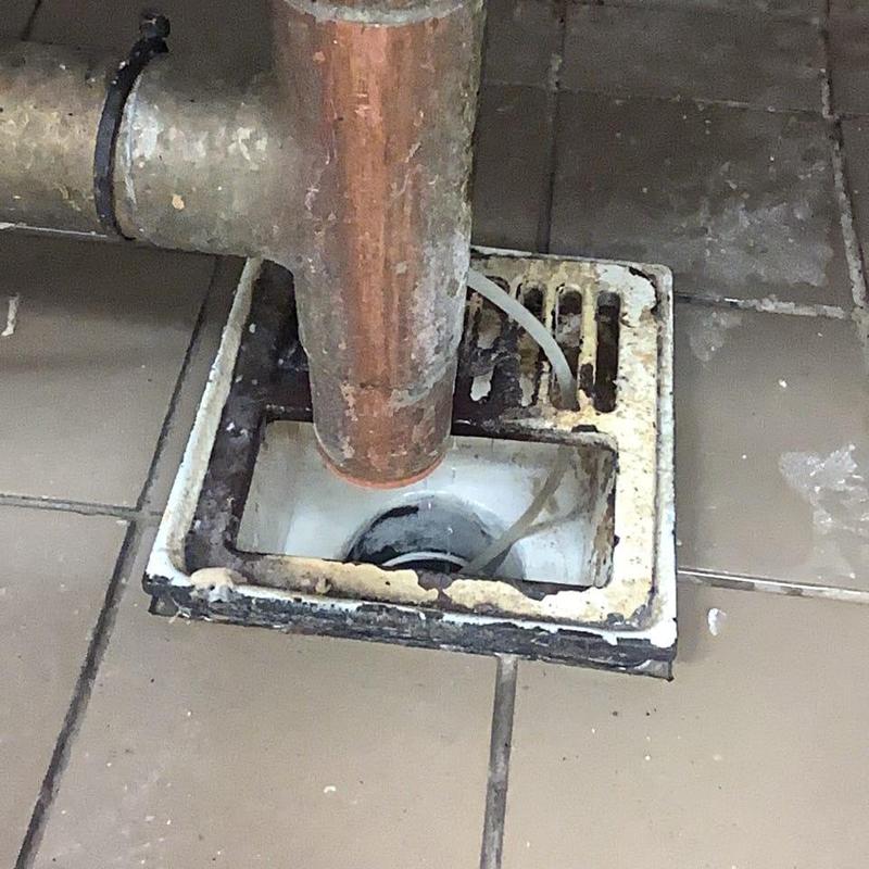 Floor drain with rusted pipe and debris buildup